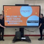 Isaac's Bronze Ambassador pupils stand with their presentation on the big screen