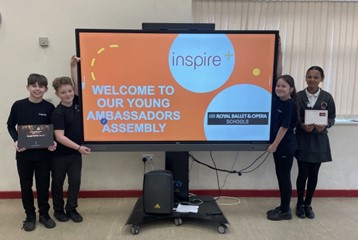 Isaac's Bronze Ambassador pupils stand with their presentation on the big screen