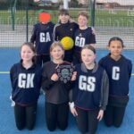 Isaac's Netball Team stand together with their winning trophy