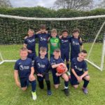 The Isaac Footy Team stand together in goal for a photo