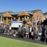 Staff and pupils stand with Lions members and the big cheque